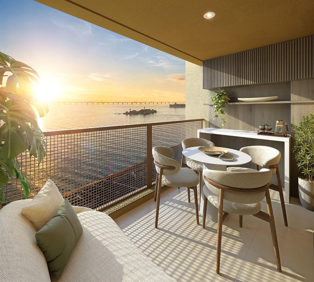 Varanda de apartamento do Residencial Erê com mesa posta e vista para o mar ao pôr do sol