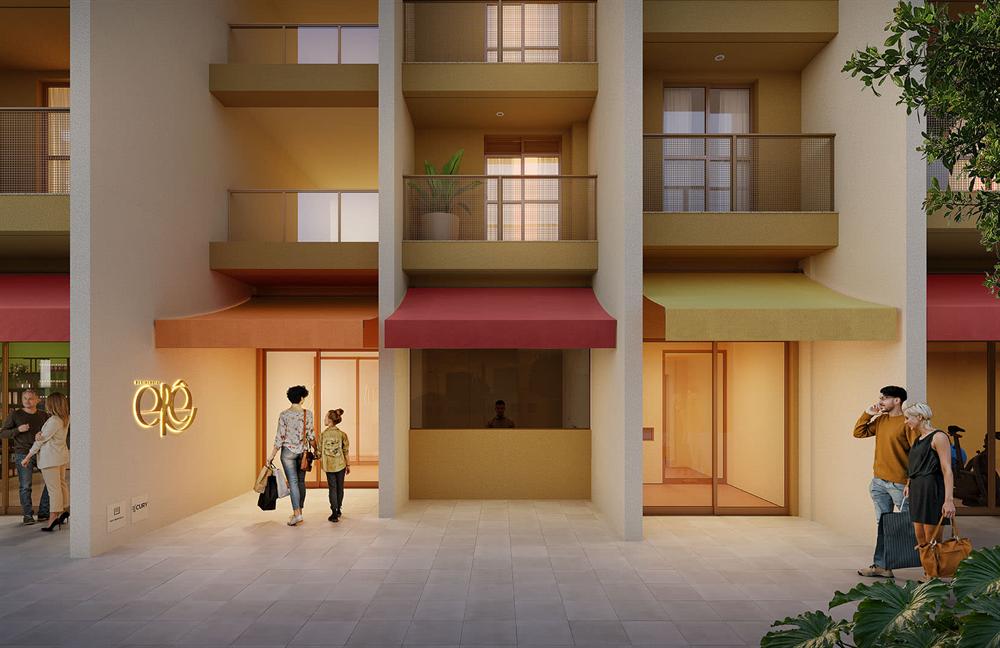 Entrada do Residencial Erê pela calçada, com a fachada iluminada ao entardecer